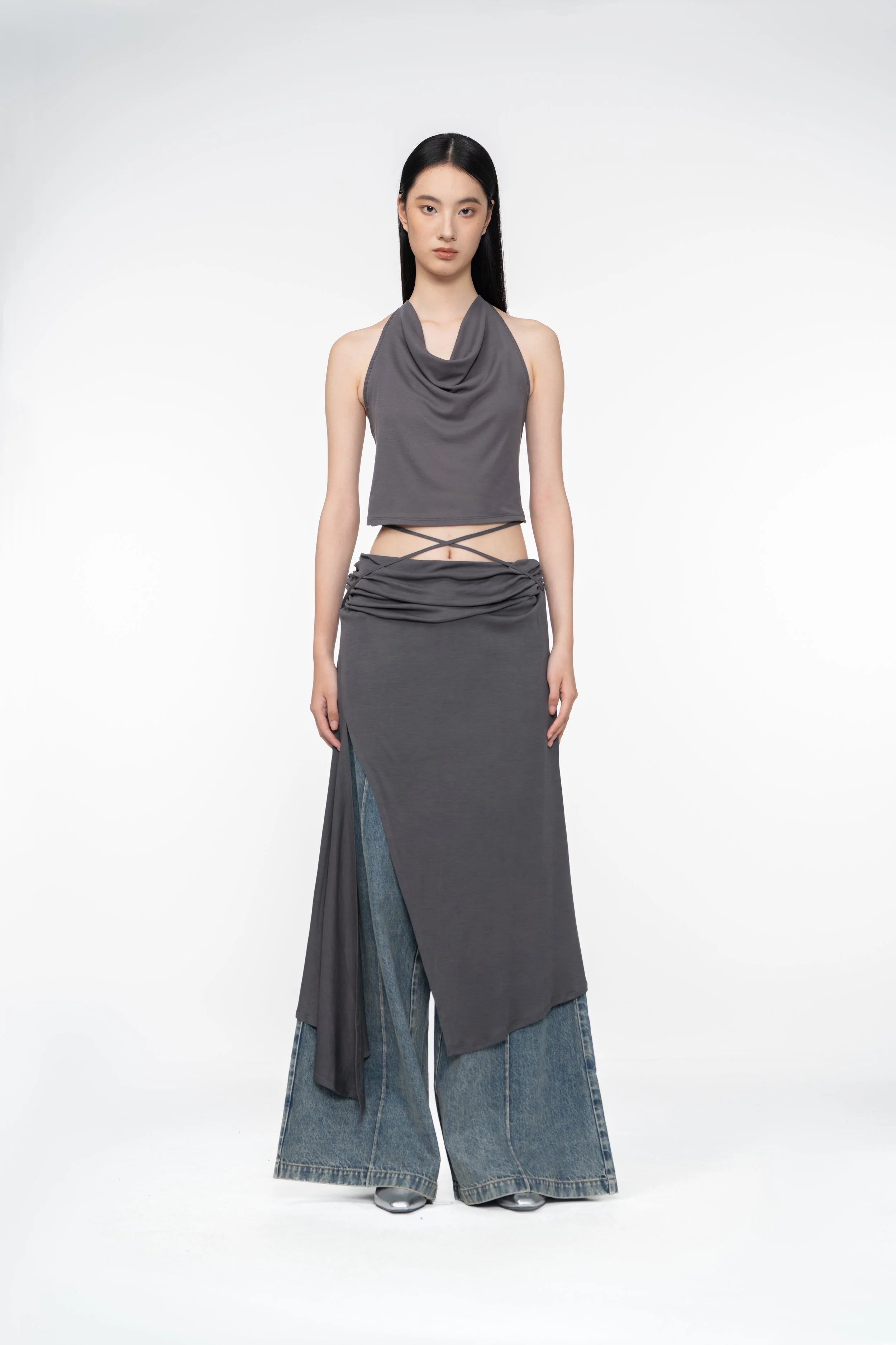 Woman wearing a gray sleeveless top and long skirt with denim accents on a white background