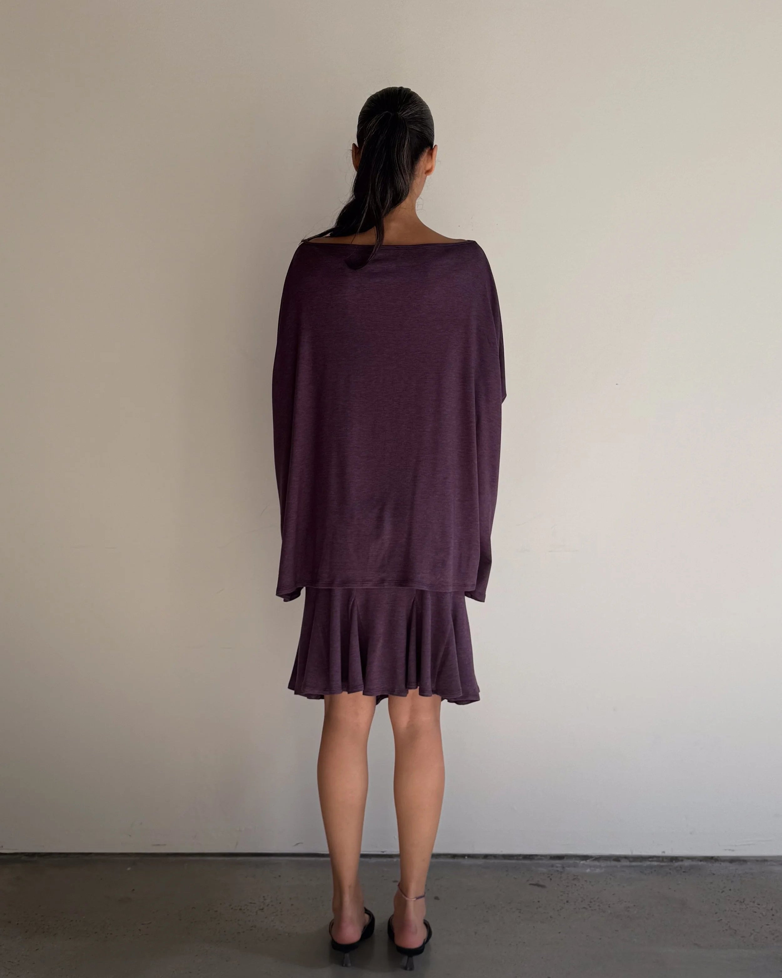 Person wearing a purple dress with a plain background