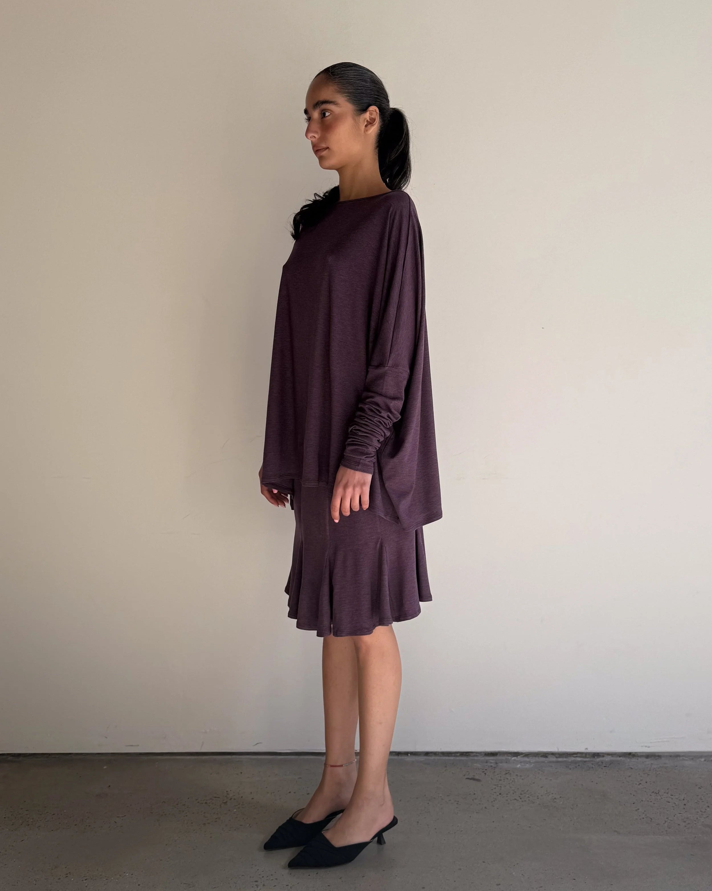 Woman wearing a long-sleeve, ruffled dress against a plain background