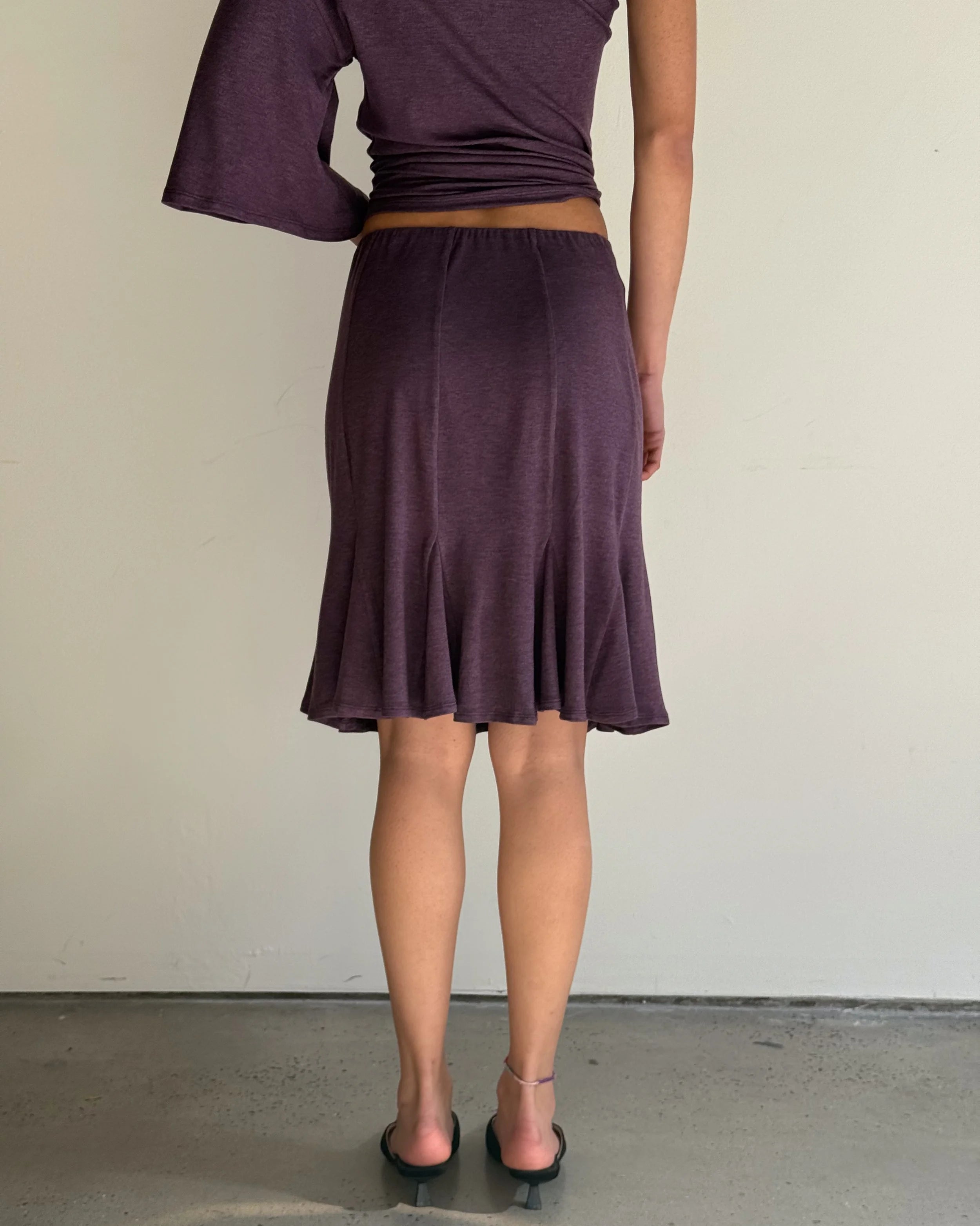 Person wearing a purple top and skirt against a plain background