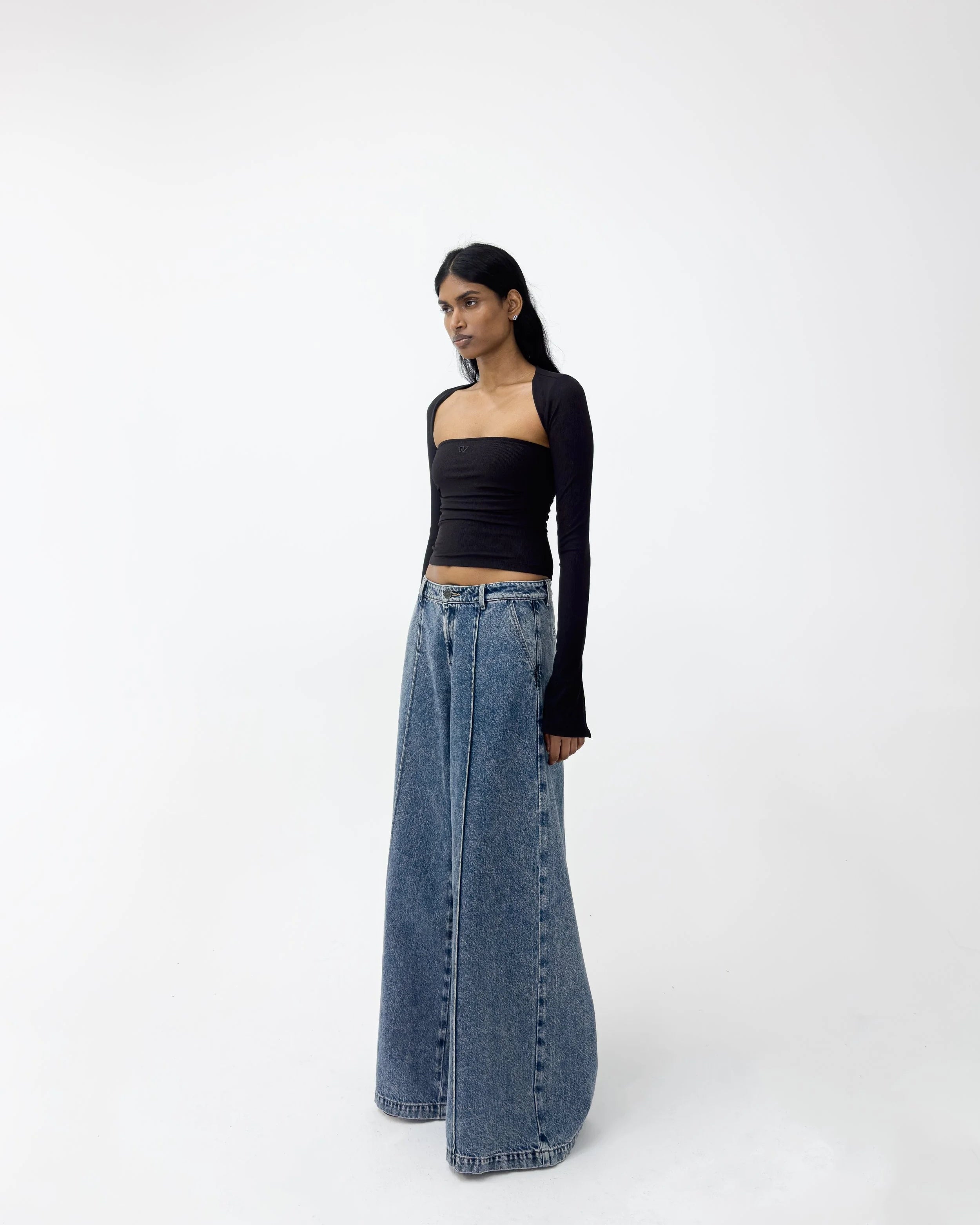 Woman wearing a black top and blue jeans on a white background
