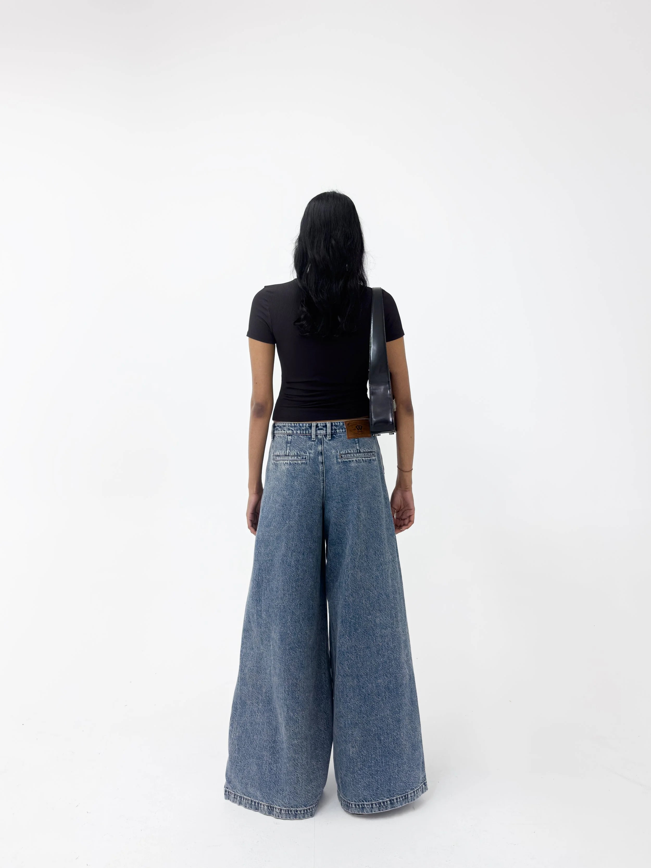 Person wearing a black top and wide-leg jeans on a white background