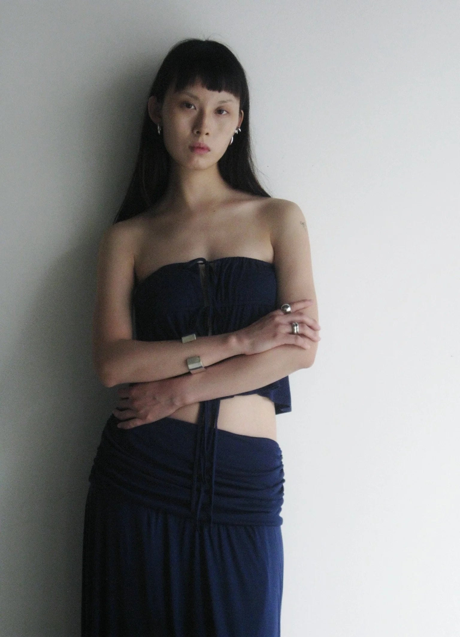 Woman wearing a strapless navy blue dress against a plain background