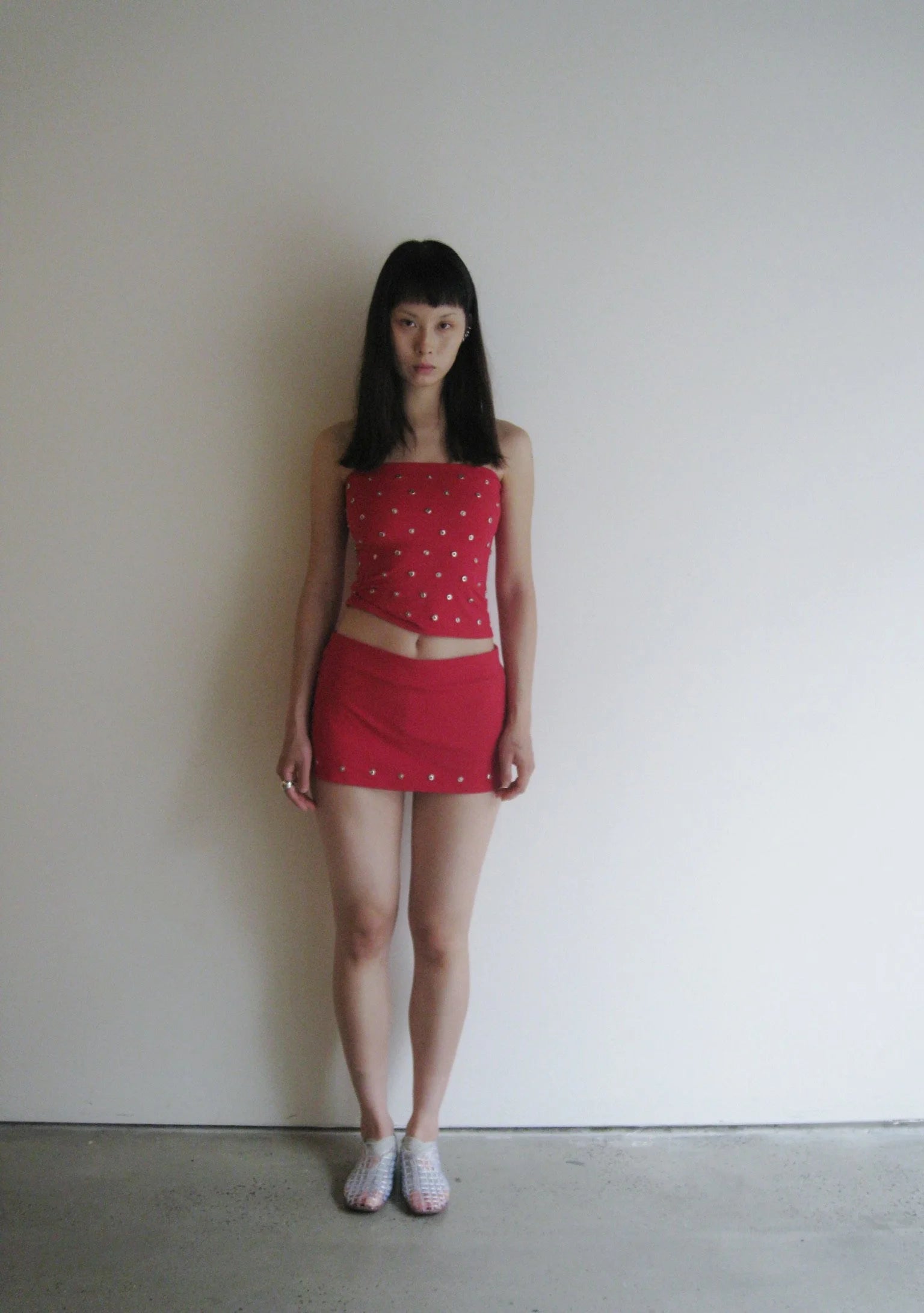 Person wearing a red outfit with white polka dots against a plain background