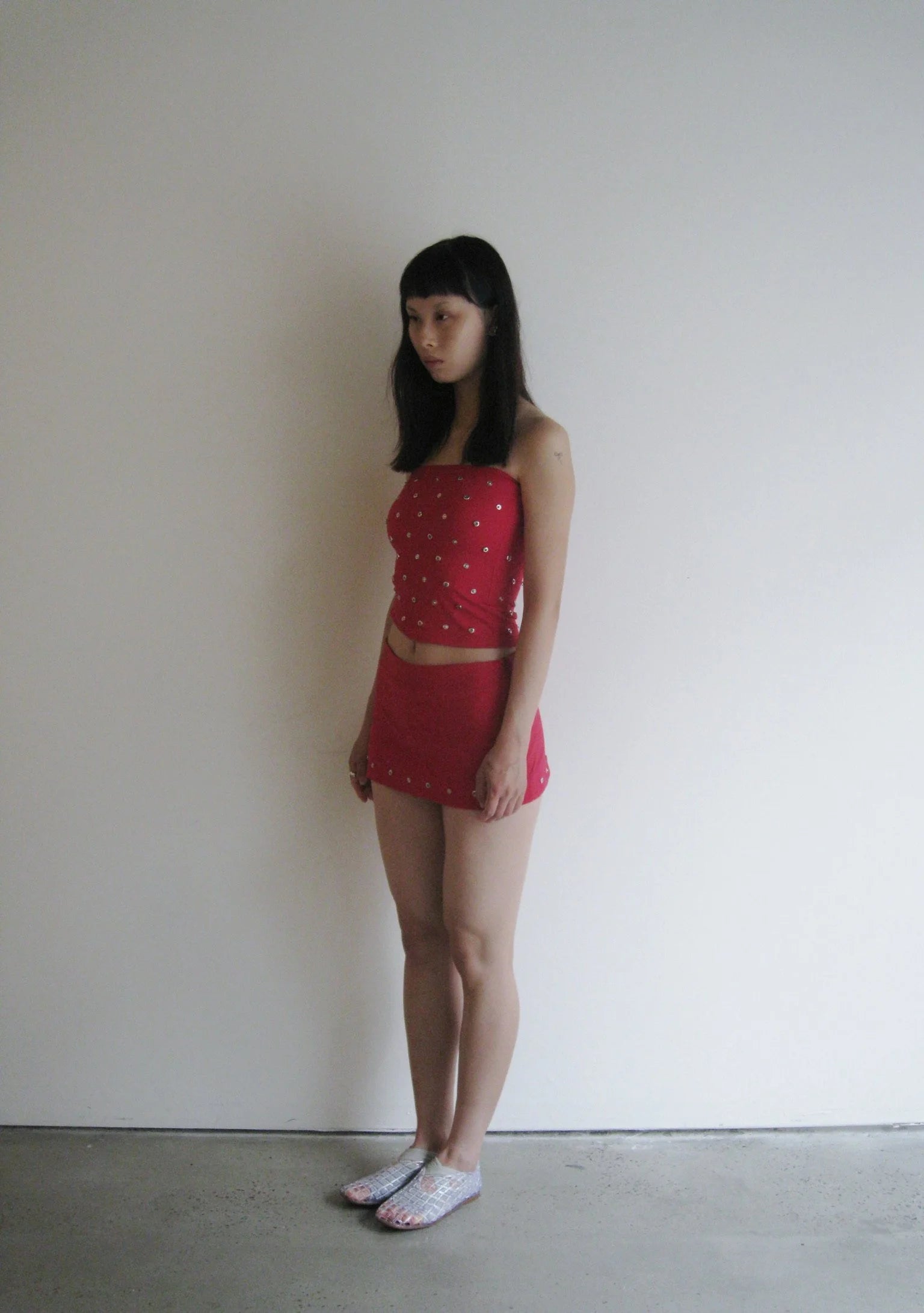 Woman wearing a red outfit with white polka dots against a plain background