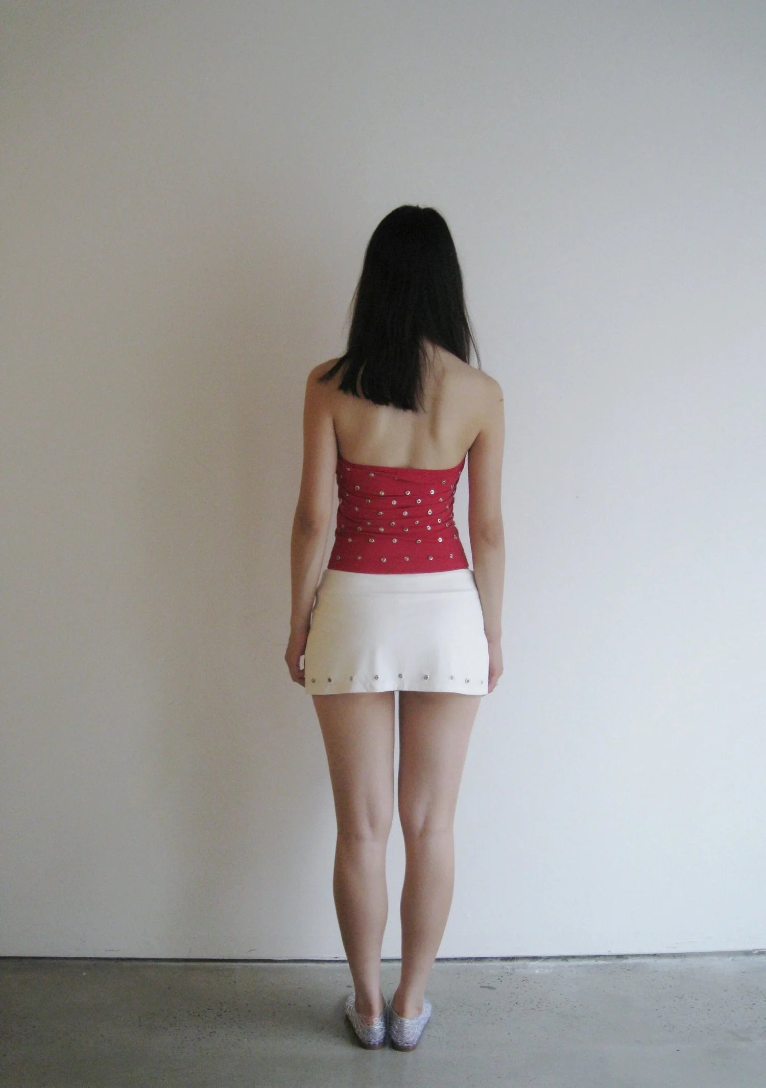 Person wearing a red top and white skirt against a plain background