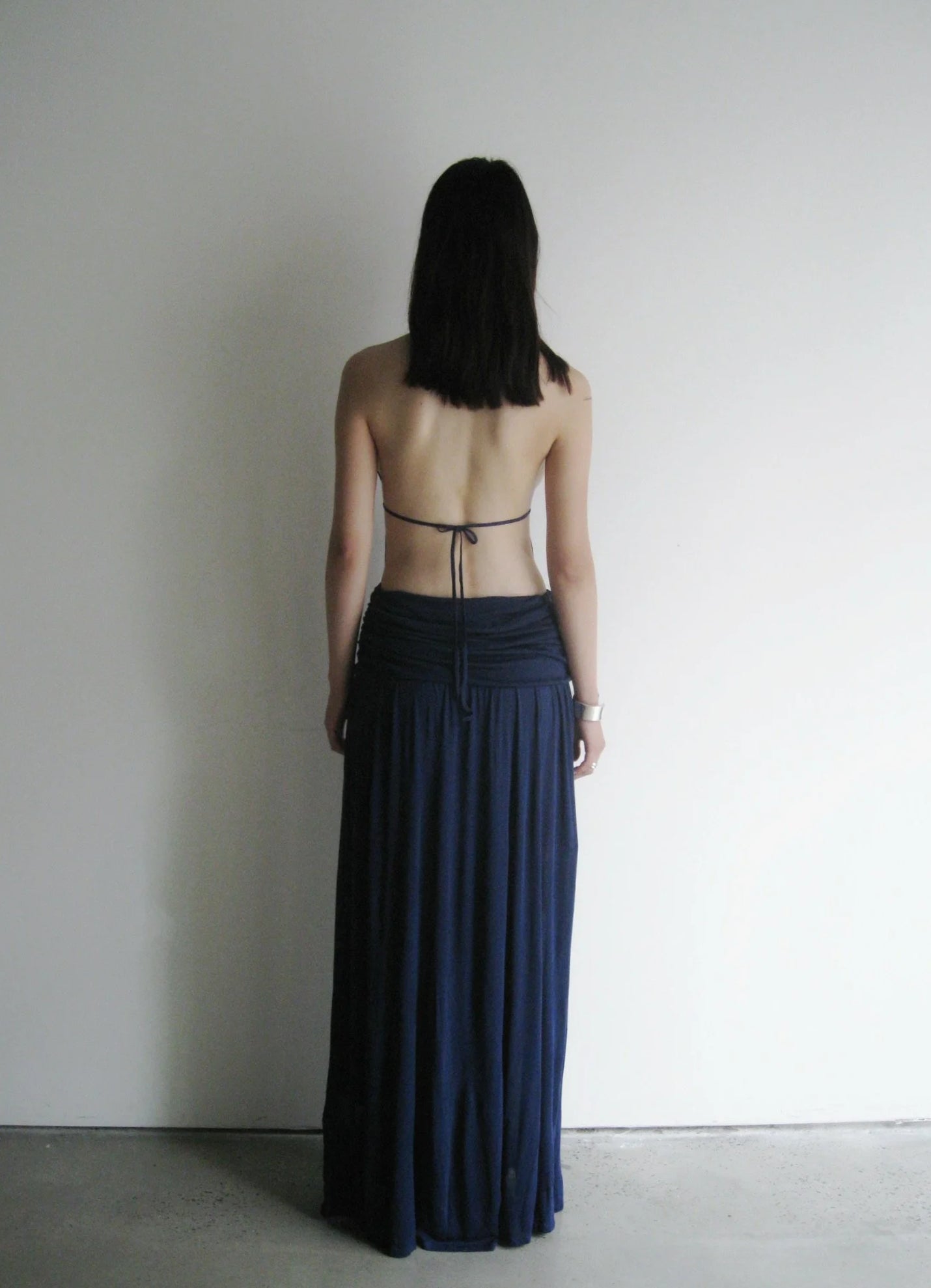 Woman wearing a long dark blue dress with a minimalistic background