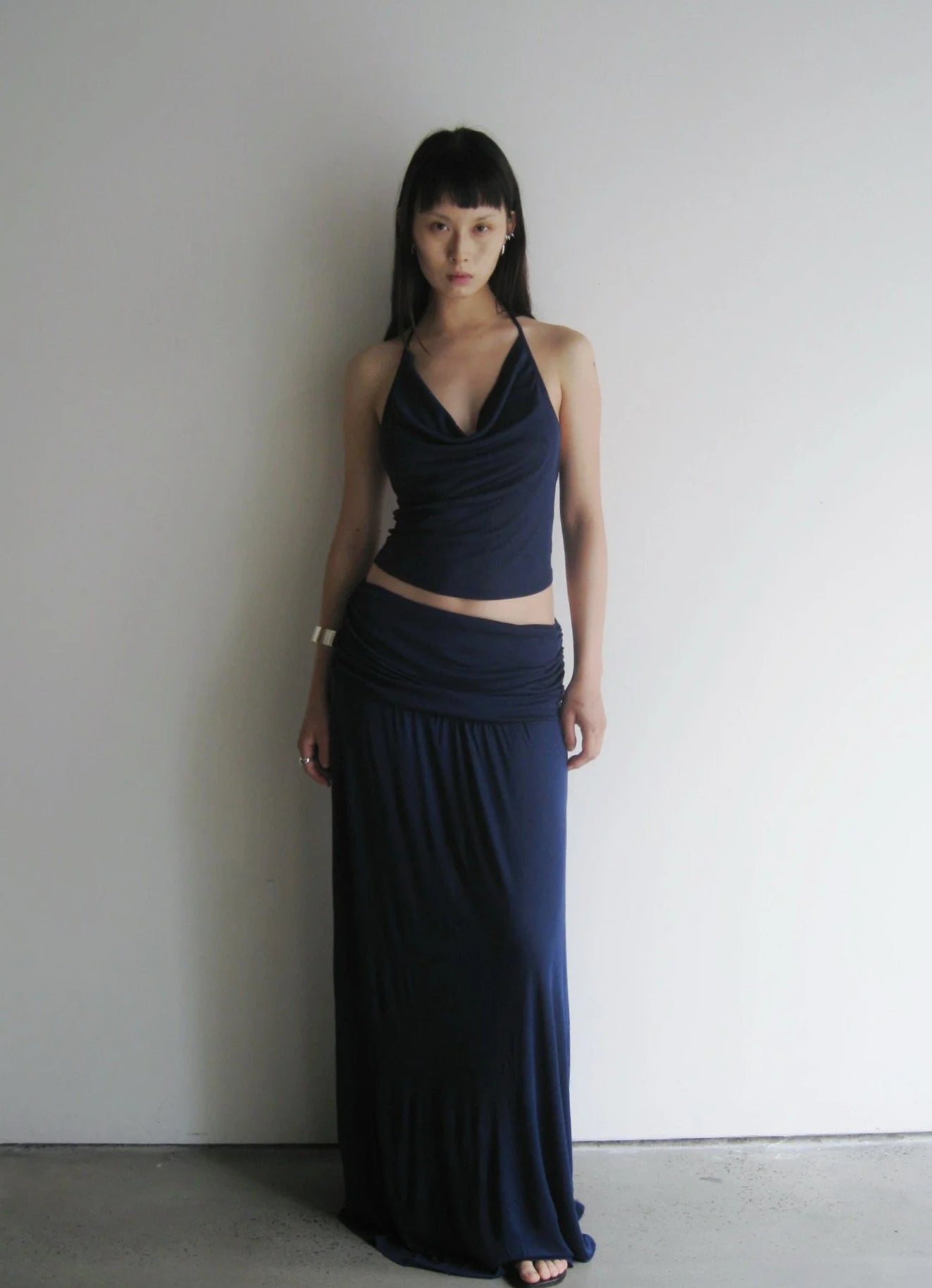 Woman wearing a navy blue two-piece outfit against a plain background